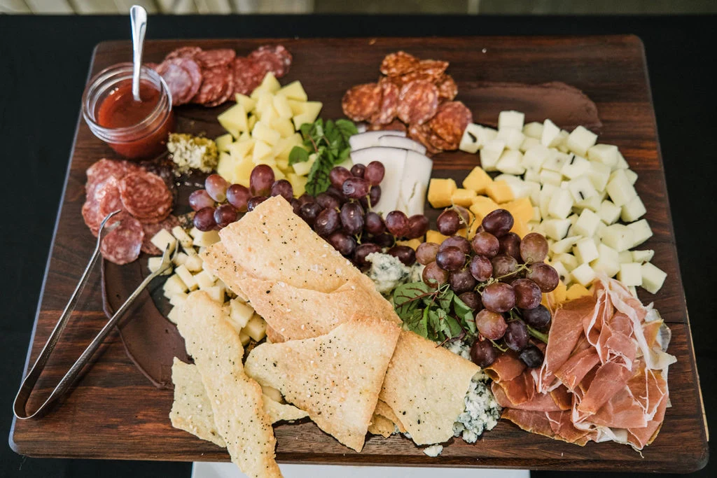 A board of cheeses, fruit, cured meats and crackers set for sharing